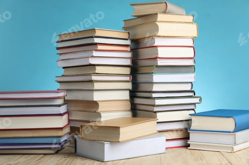 Preview: Many stacked books on wooden table against light blue background