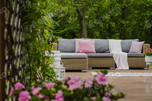 Preview: Pastel pink pillows on grey sofa in green garden with wooden terrace