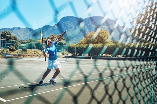 Preview: Full length shot of a handsome young sportsman playing tennis alone on a court during the day