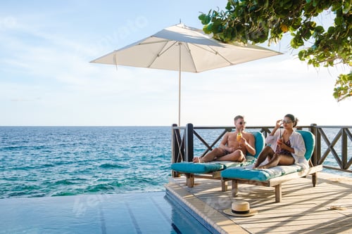 Preview: Curacao, couple man and woman mid age relaxing by the swimming pool during vacation in the Caribbean