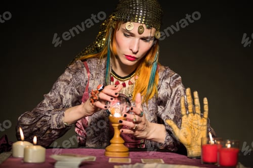 Preview: Focused female magician consulting with crystal ball