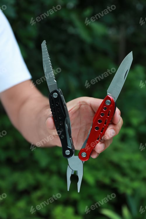 Preview: Man holding compact portable multitool outdoors, closeup
