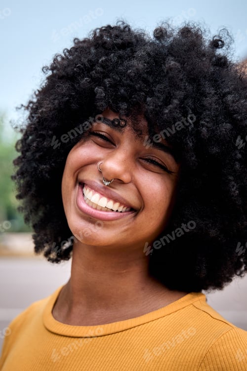 Preview: Portrait of beautiful smiling young African woman with curly hair looking camera positive expression