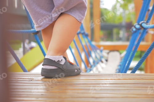 Preview: A little girl in pink shoes is standing on a wooden deck