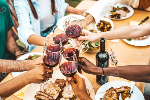 Preview: People clinking red wine glasses on rooftop dinner party