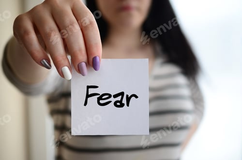 Preview: Young sad girl shows a white sticker. Caucasian brunette holding a sheet of paper with message. Fear