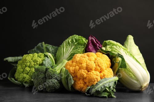 Preview: Different fresh cabbages on table against black background. Healthy food
