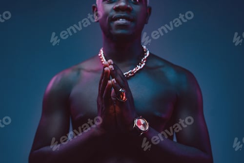 Preview: African man keeping his hands together against dark background