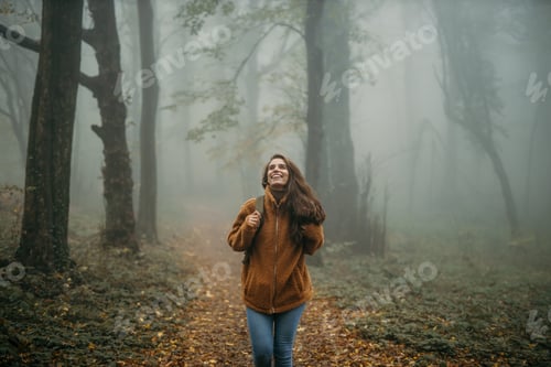 Preview: Woman hiking in foggy autumn forest enjoying nature
