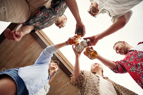 Preview: View from below. Group of people are with beer in hands having good time