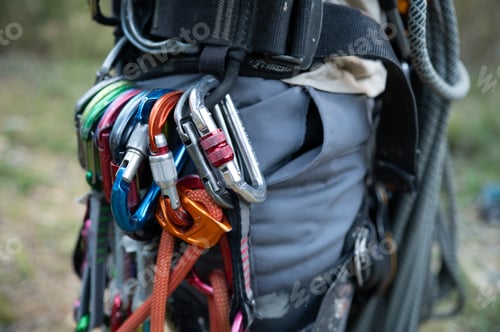 Preview: Climber wearing harness with carabiners and rope preparing for climbing