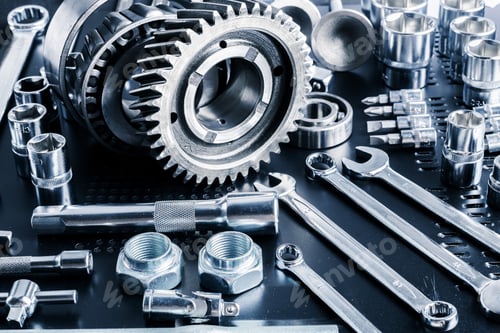 Preview: Collection of shiny metal tools and machinery parts displayed on a workbench in a well-lit garage