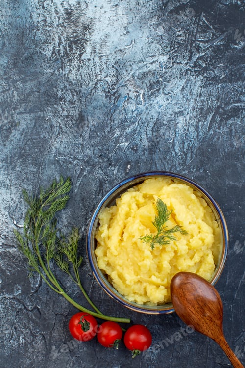 Preview: Vertical view of mashed potatoes served with dill wooden spoon fresh tomatoes on dark color