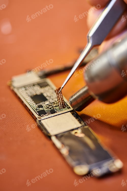 Preview: cropped view of repairman soldering chipset of electronic gadget in workshop, small business