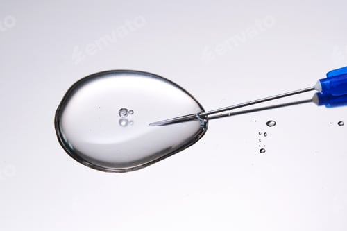Preview: A drop of medicine flowing from a syringe with a needle.