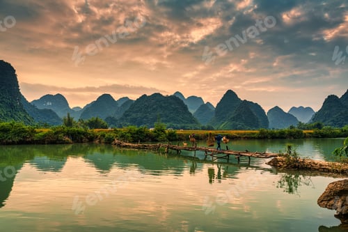 Preview: Sunset over Phong Nam Valley with rice fields and farmers crossing wooden bridge in countryside