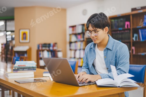 Preview: Male college students are working on laptops and searching for books to study