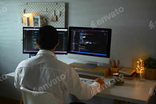 Preview: Focused male programmer working with coded data on computer screen at dark room