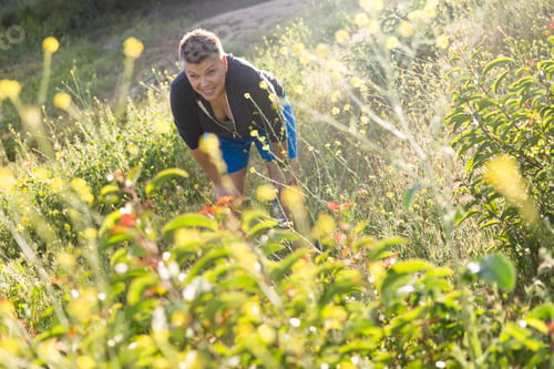Preview: Woman in wildflower meadow, bending forward hands on knees
