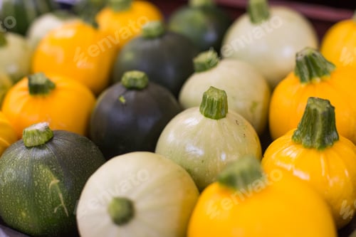 Preview: Yellow green and white pumpkins are laid in a row on the counter in the rural market. Natural Bio
