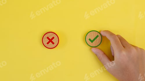 Preview: A hand is holding two wooden check marks, one red and one green