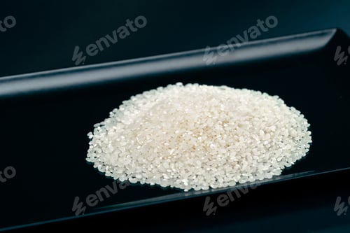 Preview: white round rice lies on black and blue background on a black long flat plate Japanese culture light