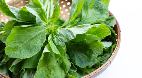 Preview: Green spinach in bamboo basket on white background.