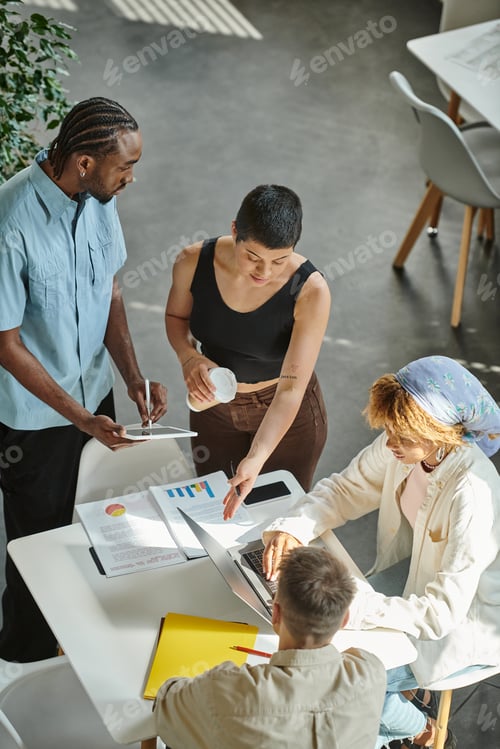 Preview: four multicultural business people working on startup ideas in coworking, gadgets and graphs