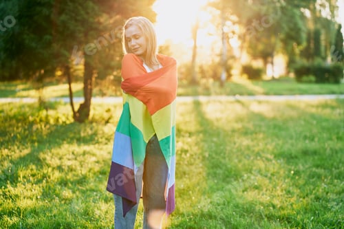 Preview: Cheerful young woman holding rainbow flag on shoulders