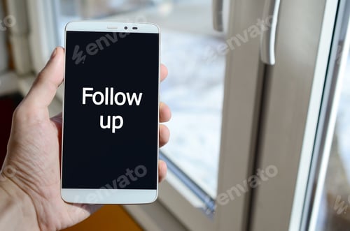 Preview: A person sees a white inscription on a black smartphone display that holds in his hand. Follow up