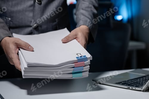 Preview: An employee was tidying up a pile of documents piled on his desk before returning home from work, A