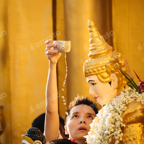 Preview: Devotee performing ritual washing of a Buddha statue during a festival