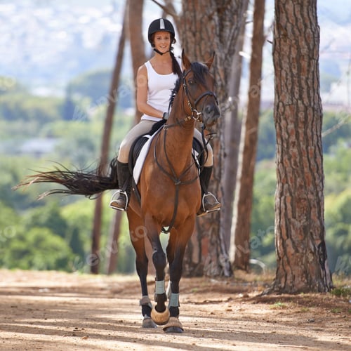 Preview: Keep calm and go horse riding. A beautiful young woman smiling while riding her chestnut horse.