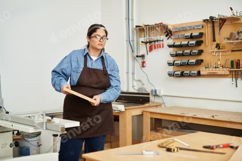 Preview: Beautiful young woman engaged in hands on woodworking at an inspiring workshop environment