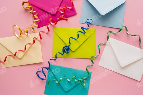 Preview: Top view of colorful serpentine on envelopes on pink background