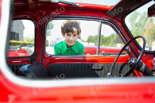 Preview: Boy looking through window of vintage automobile