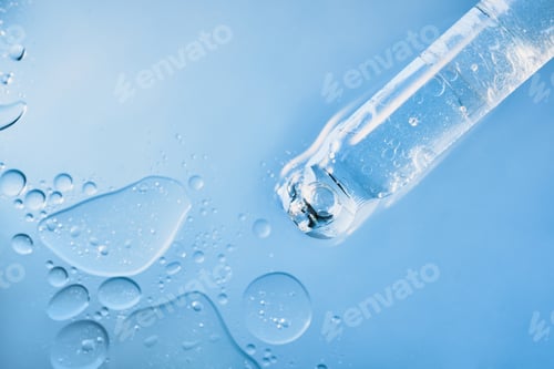 Preview: Dropper containing transparent skincare serum with bubbles on light blue liquid surface