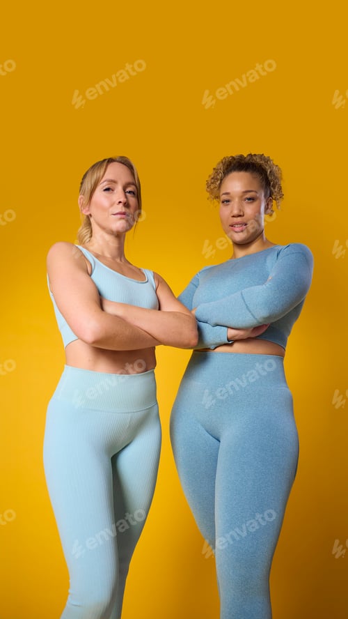 Preview: Studio Portrait Of Two Smiling Wearing Gym Fitness Clothing Exercising On Yellow Background