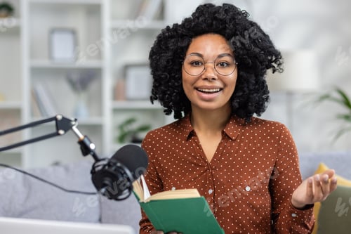 Preview: Close-up portrait of an African-American young woman sitting at home on the couch with a book in