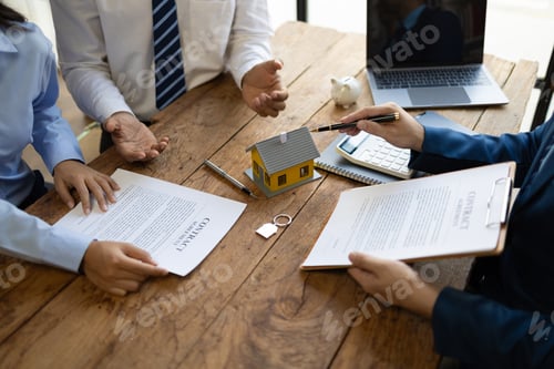 Preview: Businessman, a real estate agent, is offering a house for sale to a client using a model home.