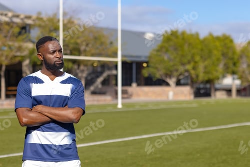 Preview: African american rugby player standing strong and fit on sports field, copy space