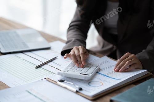 Preview: Close up view of businesswoman using calculator while analyzing the business chart in the office roo