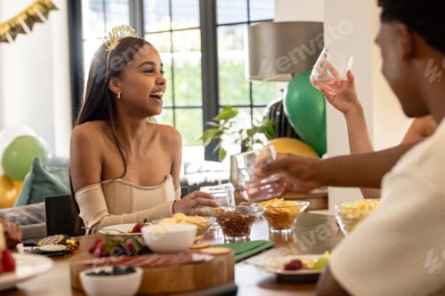 Preview: Friends celebrating at home, enjoying food and drinks, smiling and laughing together