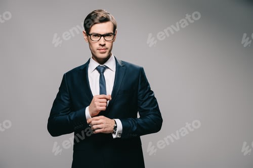 Preview: handsome businessman standing in suit on grey background