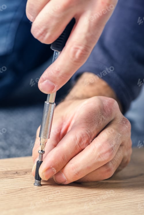 Preview: Man assembling furniture at home, hand with screwdriver
