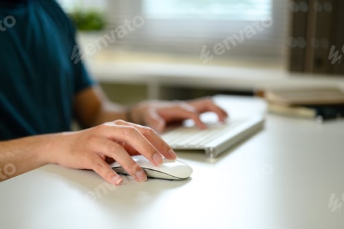 Preview: Close up of person using wireless computer mouse and keyboard on a white desk