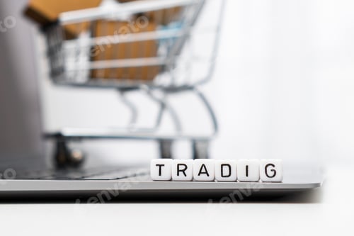 Preview: Trading words on cubes laying on the laptop and a toy shopping cart with carton boxes