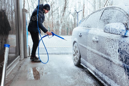 Preview: a man with a gun to apply foam on the car. self-service car wash