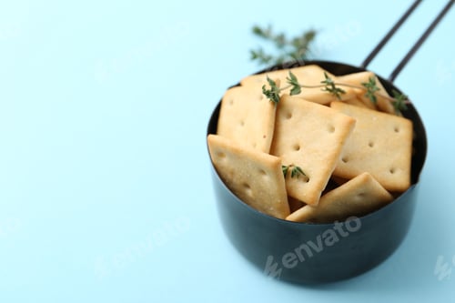 Preview: Tasty salty crackers and thyme on light blue background, closeup. Space for text
