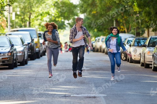 Preview: Three friends laughing and running down a sunlit city street.